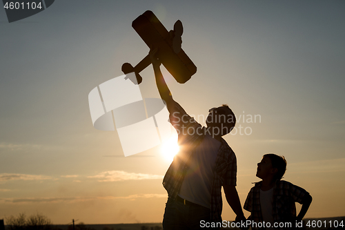 Image of Father and son playing with cardboard toy airplane