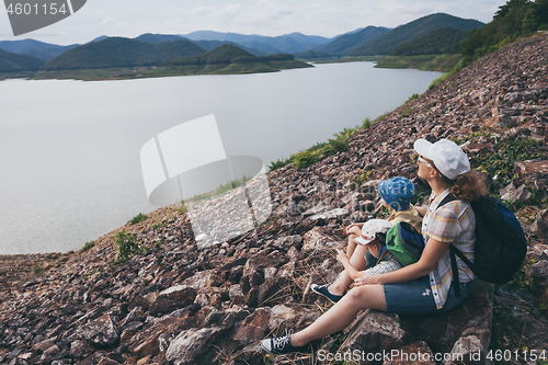 Image of Happy family sitting near a lake at the day time.