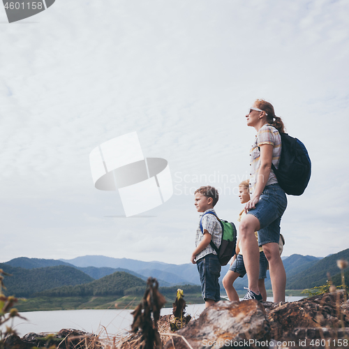 Image of Happy family standing near the lake at the day time.