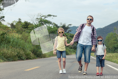 Image of Father and children walking on the road at the day time. 