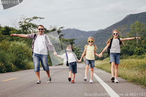 Image of Father and children walking on the road at the day time.