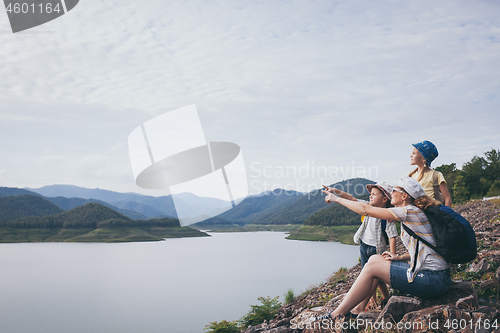 Image of Happy family standing near the lake at the day time.