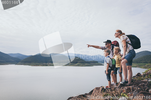 Image of Happy family standing near the lake at the day time.