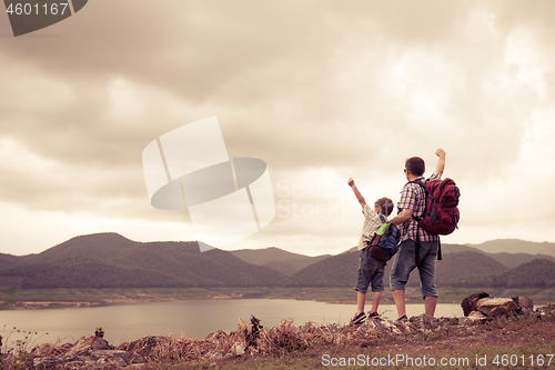 Image of Father and son standing near the lake at the day time.