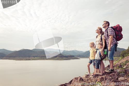 Image of Happy family standing near the lake at the day time.