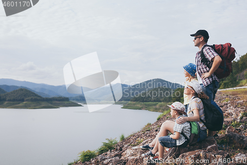 Image of Happy family standing near the lake at the day time.