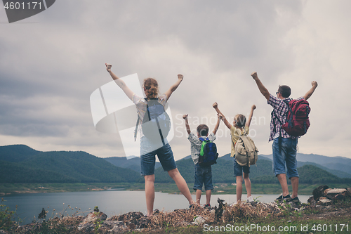 Image of Happy family standing near the lake at the day time.