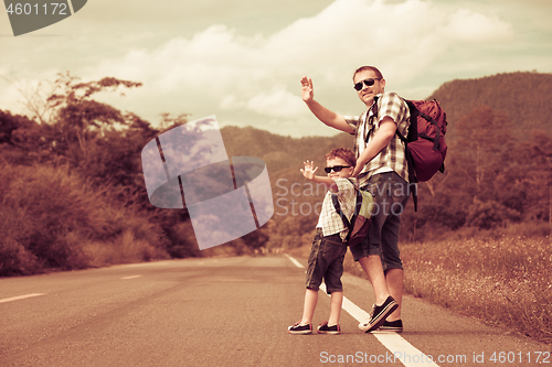 Image of Father and son walking on the road at the day time. 