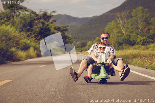 Image of Father and son playing  on the road at the day time.