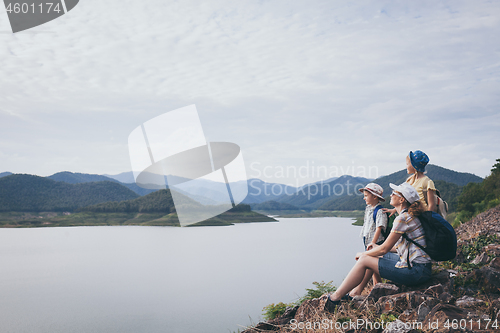 Image of Happy family standing near the lake at the day time. 