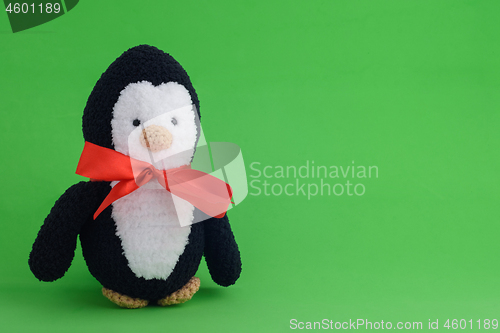 Image of Knitted toy penguin on a green background