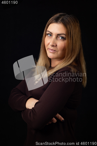 Image of Portrait of a thirty-five-year-old woman on a black background in a dark dress