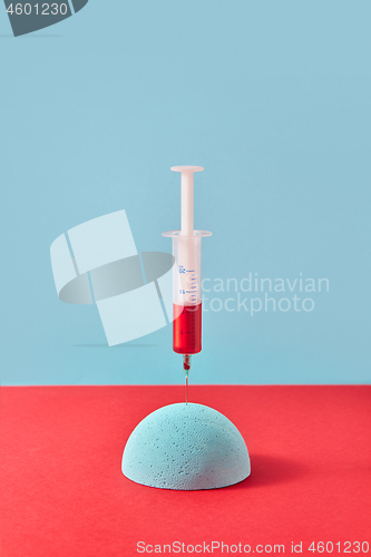 Image of Injection of syringe with red liquid into styrofoam hemisphere.