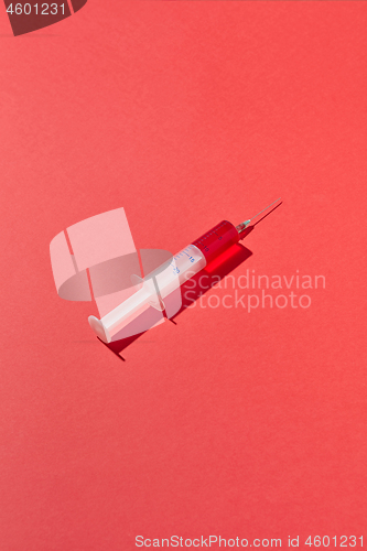 Image of Disposable syringes of red blood or vaccine with shadows.