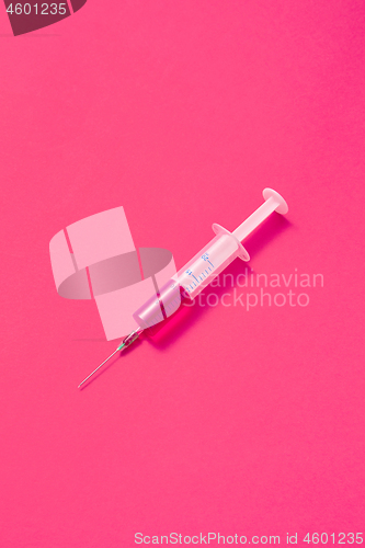 Image of Disposable syringes of hot pink vaccine with soft shadows.