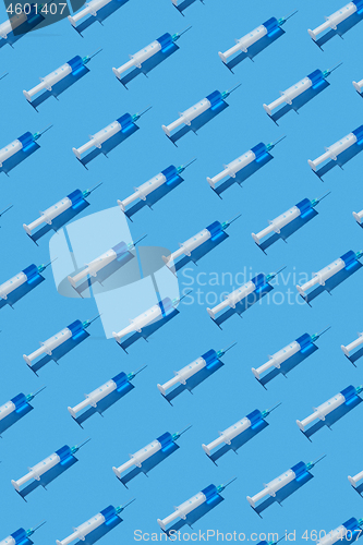 Image of Medical pattern of disposable syringes with blue injectable liquid.