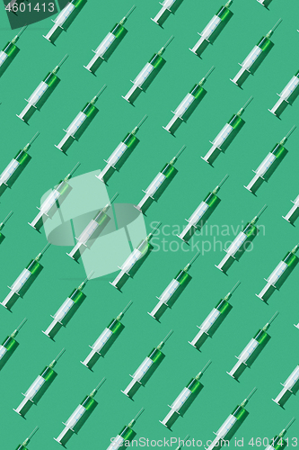 Image of Vertical pattern from disposabe syrenges with green vaccine.