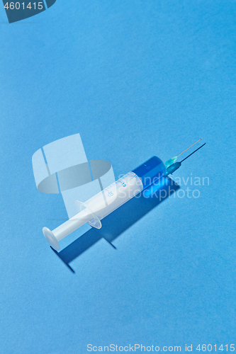 Image of Disposable syringe of blue liquid or vaccine with shadow.