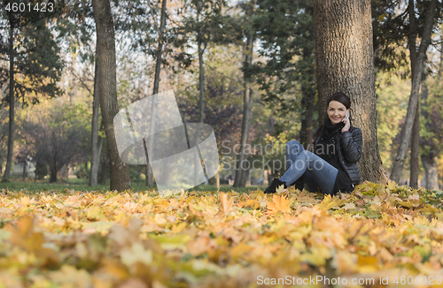 Image of Woman with a Mobile in a Forest in the Autumn