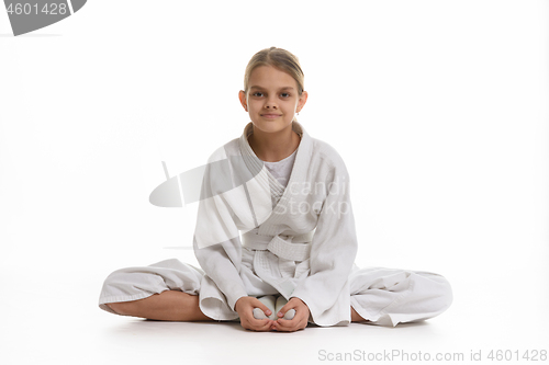 Image of Sporting girl in keikogi sits on the floor, white background