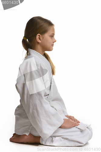 Image of Judo student sits on the floor, view from the side