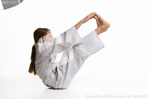 Image of A girl in a sports kekogi reaches her hands at her feet, waving a stretch