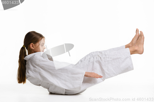 Image of Girl judoka performs warm-up and reaches her hands to her feet