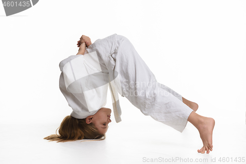 Image of Girl judo student performs exercise sticking to head and legs