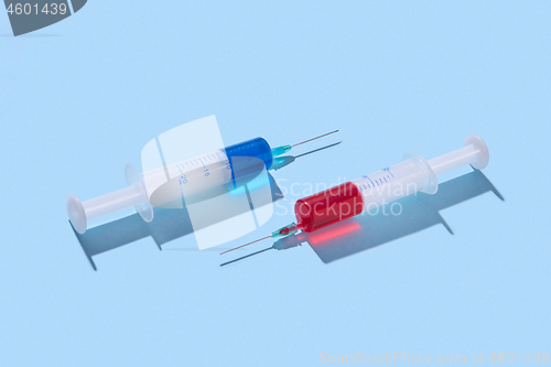 Image of Plastic syringes of red and blue vaccine with shadows.