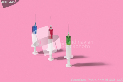 Image of Vertical plastic syrenges with colorful liquid stanging on background.
