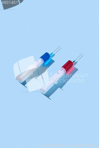 Image of Disposable syringes of red and blue vaccine with shadows.