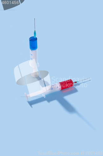 Image of Disposable syringes of red and blue vaccine with shadows.