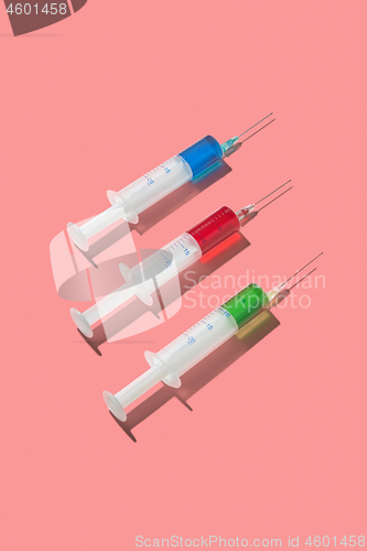 Image of Multicolored serum in three plastic disposable syrenges.