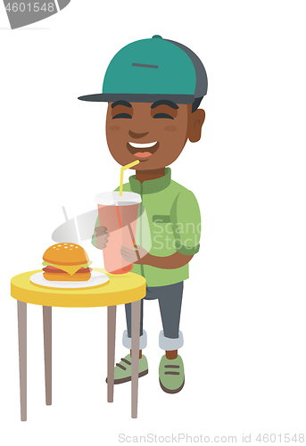 Image of Little boy drinking soda and eating cheeseburger.