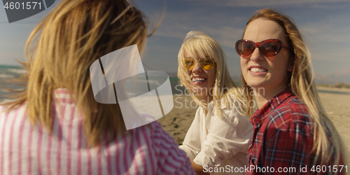 Image of Group of girlfriends having fun on beach during autumn day