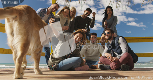 Image of Group of friends having fun on autumn day at beach