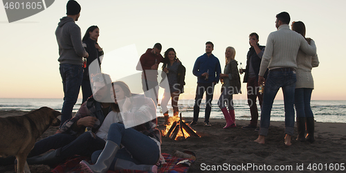 Image of Friends having fun at beach on autumn day