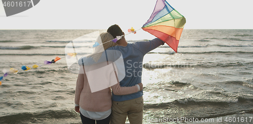 Image of Happy couple having fun with kite on beach