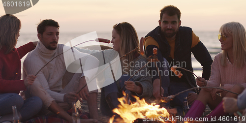 Image of Group Of Young Friends Sitting By The Fire at beach