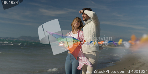 Image of Happy couple having fun with kite on beach