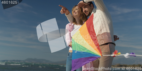 Image of Happy couple having fun with kite on beach