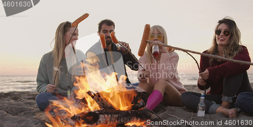 Image of Group Of Young Friends Sitting By The Fire at beach