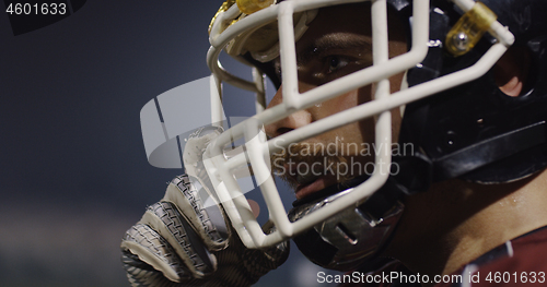 Image of American Football Player Putting On Helmet on large stadium with