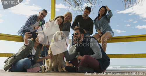 Image of Group of friends having fun on autumn day at beach