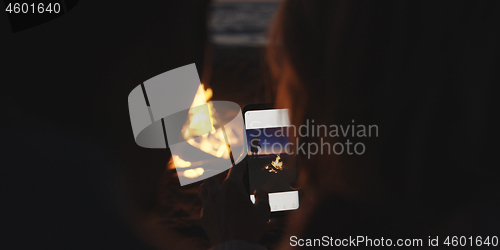 Image of Couple taking photos beside campfire on beach