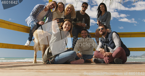 Image of Group of friends having fun on autumn day at beach