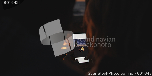 Image of Couple taking photos beside campfire on beach