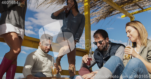 Image of Group of friends having fun on autumn day at beach