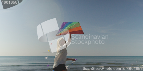 Image of Young Woman holding kite at beach on autumn day