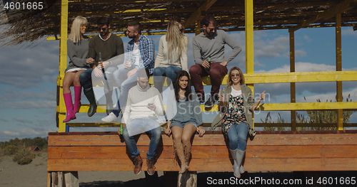 Image of Group of friends having fun on autumn day at beach